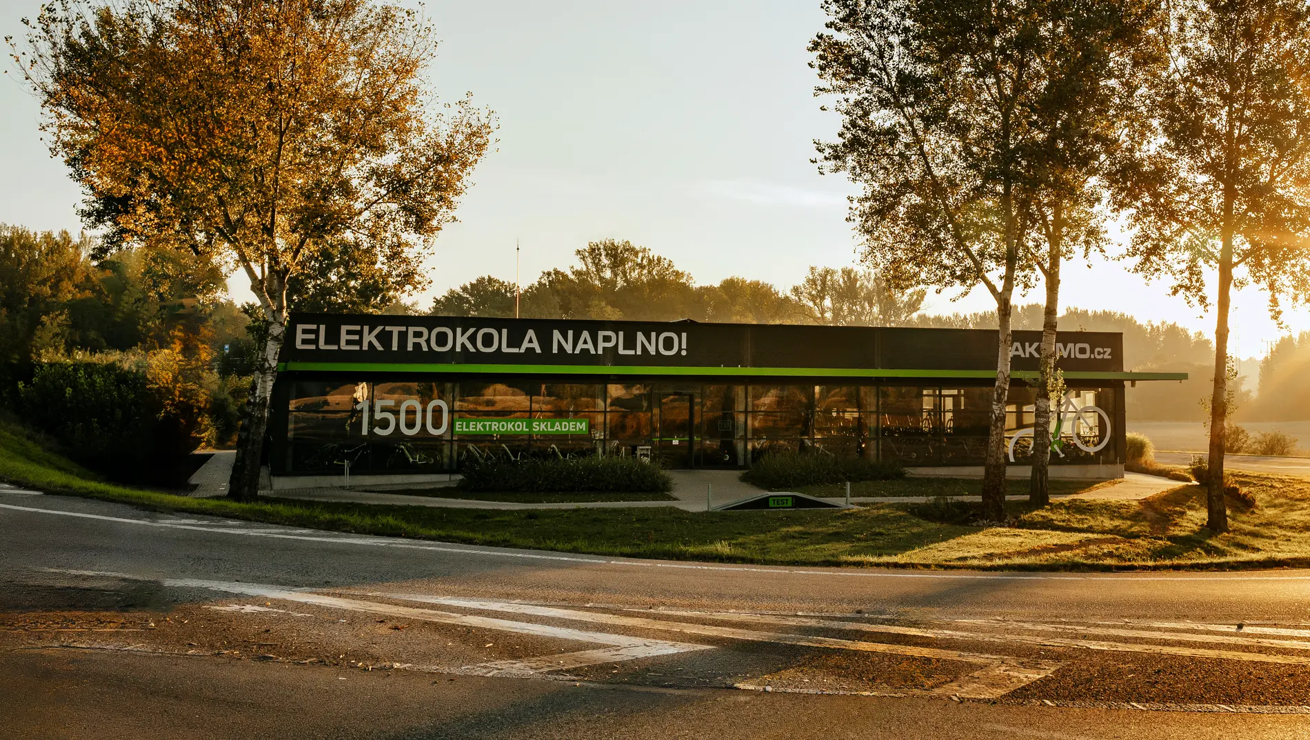 Prodejna Akumo za rozsvíceného rána, na budově nápis Elektrokola naplno a 1500 elektrokol skladem
